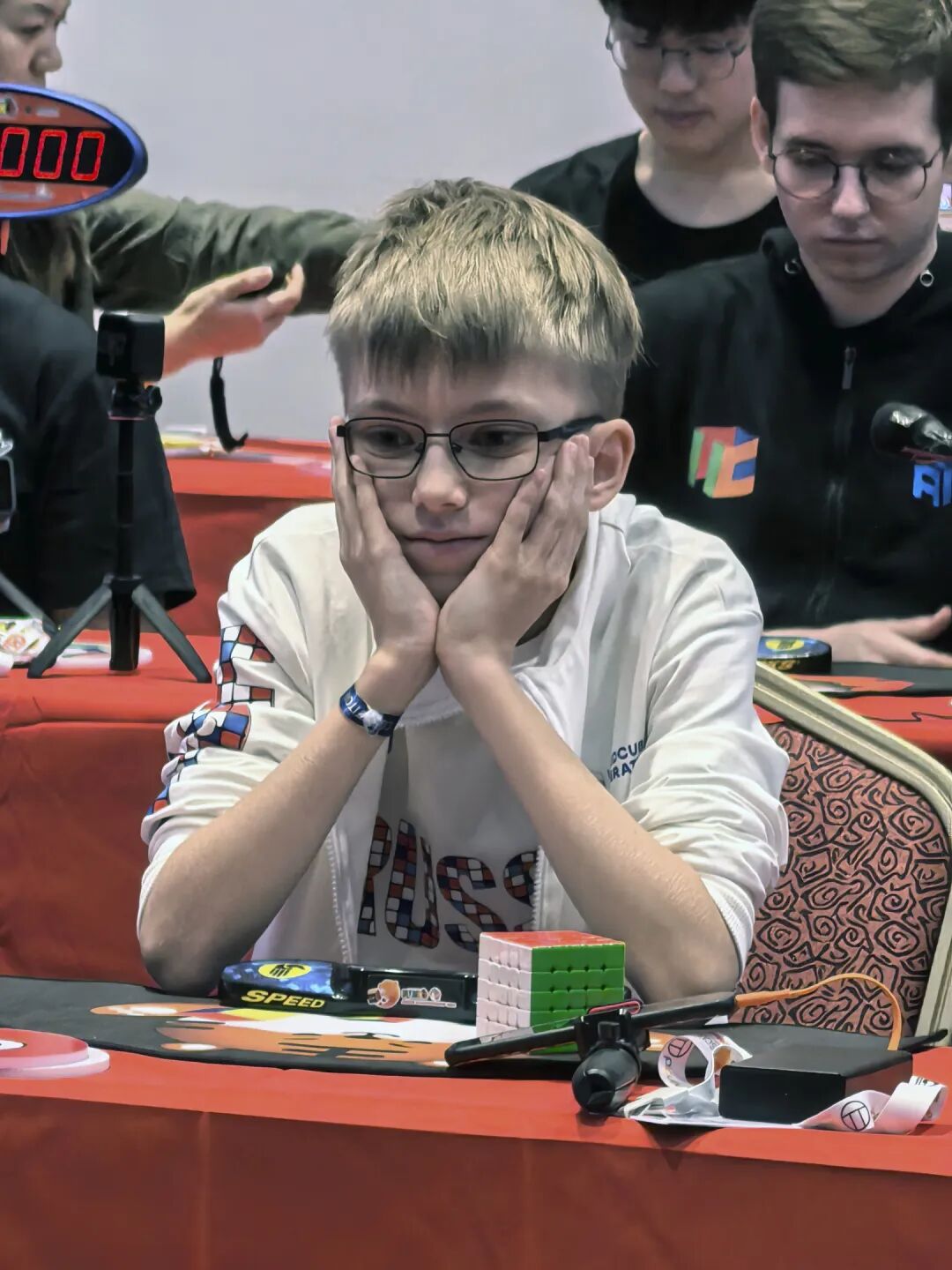 Timofei concentrating at a speed cubing competition, hands on his face