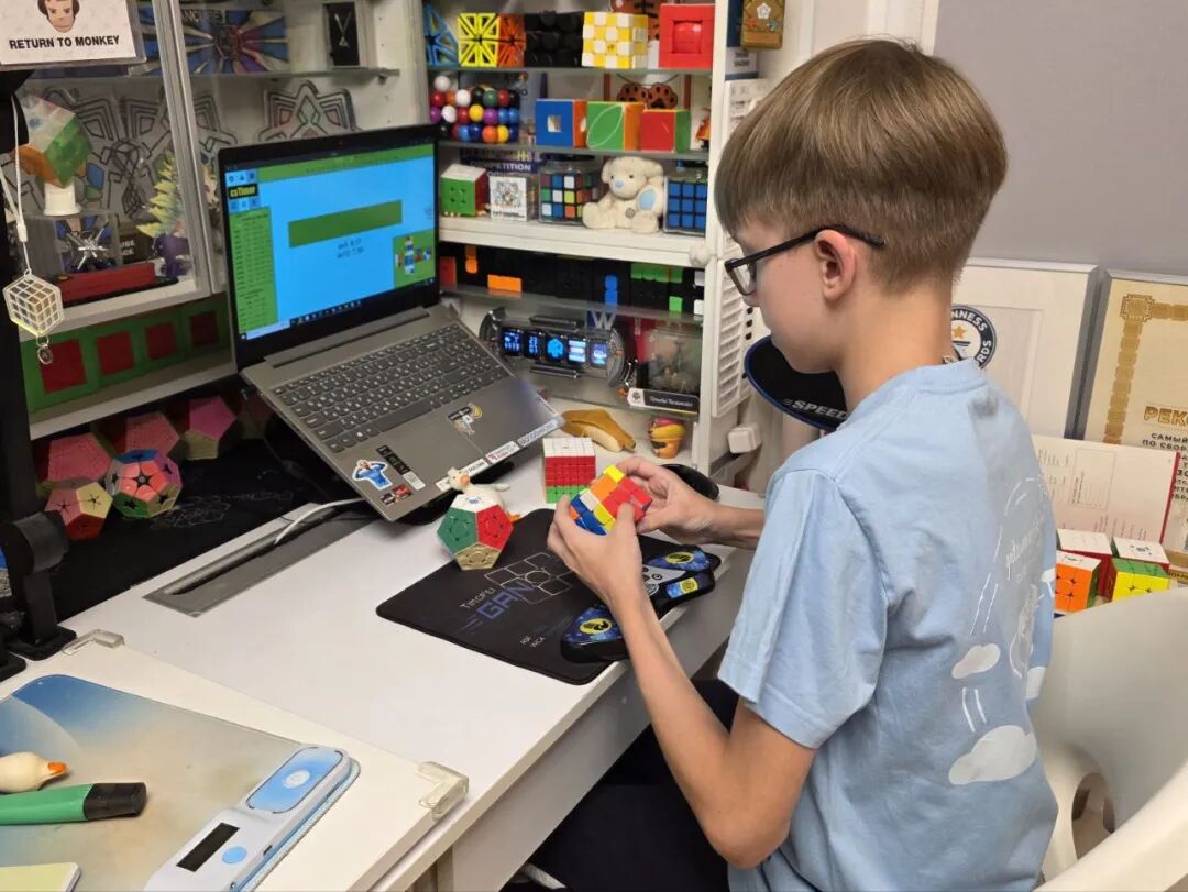 Timofei practicing cubing at his desk with a laptop and cube timer