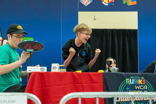 Excited speedcuber celebrates solving a cube at Rubik's World Championship event table.