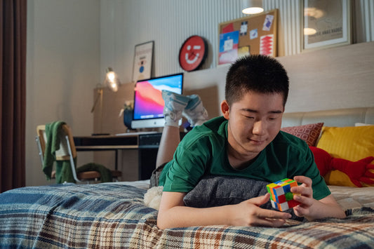 Smiling teen solving a colorful speed cube puzzle on bed in cozy bedroom